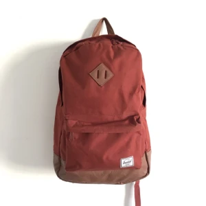  - Rostfärgad ryggsäck i en klassisk modell från märket Herschel! Den har två fack på insidan, ett för datorn/mapparna och ett för pennor. Sedan ett på utsidan där man kan stoppa lite allt möjligt i. Jättebra väska för den som har mycket saker att bära! 