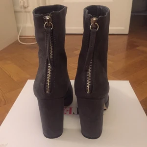  - Helt nya skor, endast testade inomhus.  Fakemocka med en kromad dragkedja baktill.  I färgen mörkgrå, väldigt fina!!   Kan fraktas mot kostnaden