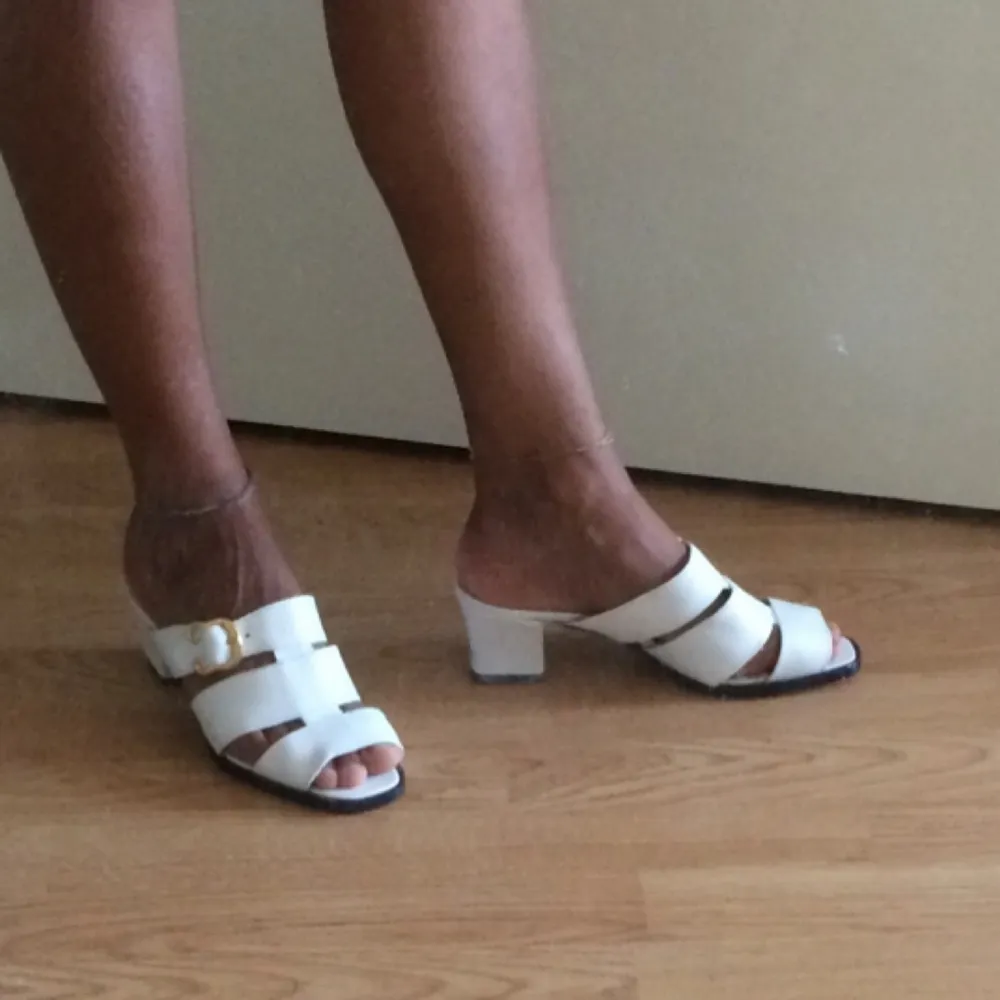 White leather imitation slip-ins with golden buckle on the side. Low heel, comfortable to walk in. Fits small 37. Note: inner side of left heel has a black mark that can be removed. Hence the low price. . Skor.