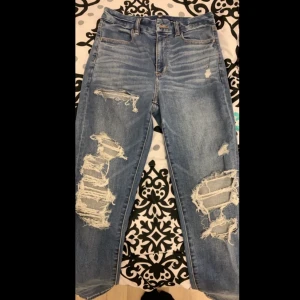 American Eagle slitna jeans - Superstretchiga och högmidjade slitna jeans från American Eagle. De är i storlek 8 (ca 40-42) men är stretchiga så de skulle passa folk mellan storlekarna 40-44. De är i väldigt bra skick och säljs pga att de knappast använts.