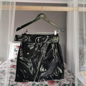 En kort kjol från H&M i svart tyg med lackad effekt [frakt tillkommer] 