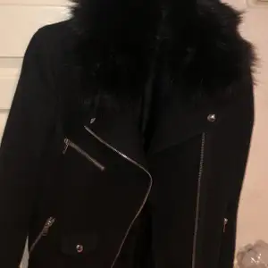 En svart kappa från Zara med pälskrage och silvriga detaljer. Köpt för cirka 2 år sedan knappt använd.