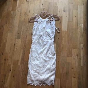  - Vit klänning endast använd en gång. Öppen i ryggen med en knytning vit typ nacken/skuldrorna