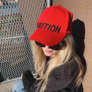  - Röd keps med texten ”Caution” framtill