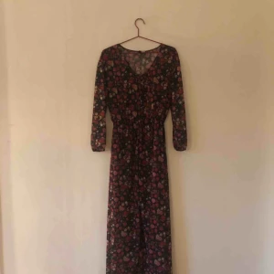  - Blommig långklänning i fint skick. 100% polyester. Tunt tyg som man ser igenom. Passar fint till både kjol/klänning eller byxa undertill. 