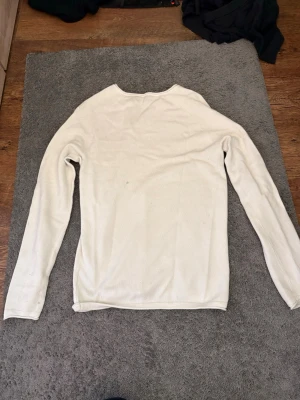 Vit långärmad tröja i bomull - En enkel och stilren vit långärmad tröja med rund hals. Tillverkad i mjukt bomullsmaterial som känns skönt mot huden. Perfekt att matcha med jeans eller under en jacka. Tröjan har en clean look utan tryck eller mönster.