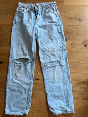 Baggy ljusblå jeans med hål - Jättesnygga populära jeans med hål från Gina som är baggy. Använda några gånger, passar mig som är 163Cm och Xs/S. De är storlek 36! Pris kan diskuteras!🤗inga deffekter!