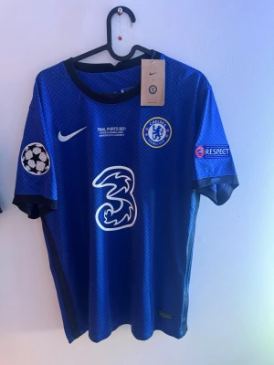 Chelsea matchtröja Werner 11 blå - Chelsea FC matchtröja i blått med svarta detaljer, Champions League-märken på ärmarna och tryck av Werner 11 på ryggen. Tröjan har klubbmärke, Nike-logga och sponsortryck framtill. Tillverkad i lätt och ventilerande material, perfekt för fotboll.