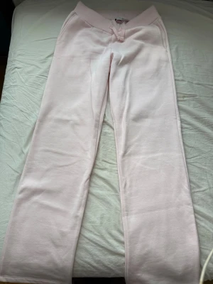 Ljusrosa mjukisbyxor med dragsko XS - Supersköna ljusrosa mjukisbyxor med bred ribbad midja och dragsko. Byxorna har raka ben och sidofickor, perfekta för chill dagar. Tillverkade i mjukt bomullsmaterial som känns riktigt bekvämt mot huden.