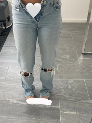 Ljusblå jeans med hål på knäna - Säljer ett par fina ljusblå jeans från Zara med hög midja och raka ben. Jeansen är i fint skick och har en klassisk modell som passar till det mesta. Säljer dem eftersom de tyvärr är lite för små för mig. 