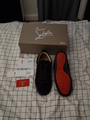Svarta Christian Louboutin Sneakers - Stilrena svarta sneakers från Christian Louboutin i mocka med klassisk röd sula. Lågt skaft, svarta skosnören och diskret design. Riktigt sköna och passar bra med alla olika typer av outfita💪 Passar för strl 43-44. Priset är inte fast, har du några frågor är det bara att skriva! 😁