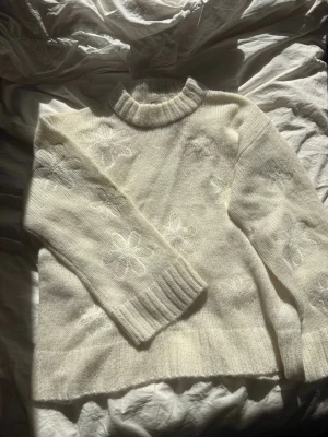 Vit stickad tröja Gina Tricot  - Mysig vit stickad tröja från Gina Tricot i ullmix. Tröjan har broderade blommor i samma färg, ribbad halsringning, ärmslut och nederkant. Perfekt för dig som gillar en enkel men söt look.