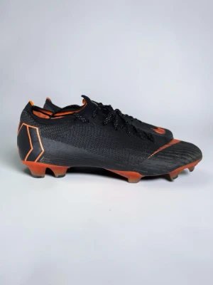 Mercurial vapor 12 - Storlek: 44  Stilren svart färgställning med orange (“Total Orange”) accenter i Nike-swooshen och detaljerna, samt orangea dubbar. Flyknit-konstruktion med ACC-teknik (All Conditions Control) för bra bollkontroll och tight passform.  ✅ Bra skick ✅ Storlek 44 ✅ Äkta vara  Hör av dig vid frågor eller om du vill ha fler bilder! ⚽️📦