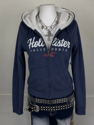 Marinblå Hollister hoodie med foder - Hollister 2000s Navy Y2K Zip-Up  Hollister 2000s Y2K zip-up i mörkblå/navy 💙  • Storlek märkt: L • Passar bäst: S-M • Passform: Women’s • Färg: Navy • Era: 2000s / Y2K • Märke: Hollister  Vintage Y2K-modell med en snygg, klassisk Hollister-look. Perfekt att styla med jeans, kjol eller tracksuit.  📦 Skickas snabbt och noggrant packad!