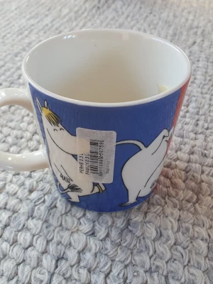 Muminmugg Familjen Mumin  - Felfri mugg med etikett kvar. Säljer fler Muminmuggar så kika gärna på mina övriga annonser också. Packar mycket noggrant. 