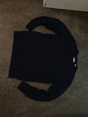 Mörkblå tröja från Jack & Jones - En stilren mörkblå tröja från Jack & Jones med rund halsringning och långa ärmar. Perfekt att matcha med jeans eller chinos för en clean look. Materialet känns mjukt och bekvämt mot huden.