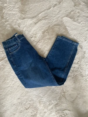 Mörkblå raka jeans - Säljer ett par mörkblå jeans med rak passform och klassisk femficksdesign. Jeansen har normal midja och är tillverkade i ett robust denimtyg. Perfekta för en avslappnad och stilren look. Helt nya aldrig använt 