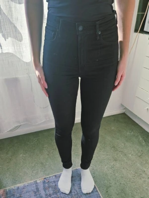 Levi's svarta jeans st w29 L30 - Säljer ett par svarta leggings med hög midja och tight passform. De har klassisk design med fickor bak och är tillverkade i stretchigt material som sitter snyggt längs benen. Perfekta för dig som gillar en enkel och stilren look.