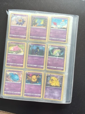 Pokémonkort i samlarpärm - Säljer en samling Pokémonkort i en genomskinlig plastpärm. Korten har olika motiv och färger, bland annat Starmie, Cosmog, Drowzee, Xerneas och Zamazenta. Perfekt för dig som gillar att samla eller spela Pokémonkort.