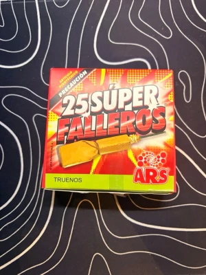 25-pack fyrverkeripjäser ARS - En oöppnad ask med 25 stycken fyrverkeripjäser av märket ARS, modell Súper Fallero. Pjäserna är inslagna i brunt papper och har gröna stubiner. Perfekt för dig som gillar smällare och vill ha något extra till firandet. Skriv om du har några frågor👌❤️