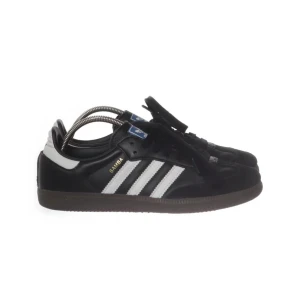Adidas Samba svartvita sneakers - Klassiska Adidas Samba sneakers i svart läder med vita detaljer och de ikoniska tre ränderna på sidan. Låg modell med brun gummisula och svart snörning. Perfekta för en sportig och stilren look.