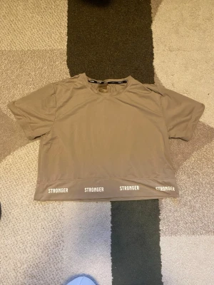 Beige tränings T-shirt - Snygg beige croppad tränings t-shirt från Stronger. Mycket bra skick!🫶