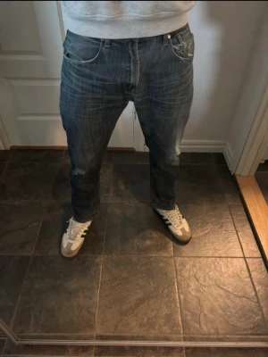 Mörkblå raka jeans med slitningar - Säljer ett par mörkblå jeans med raka ben och snygga slitningar, storlek 33/32. Hör av er vid mer frågor eller bilder pris kan diskuteras