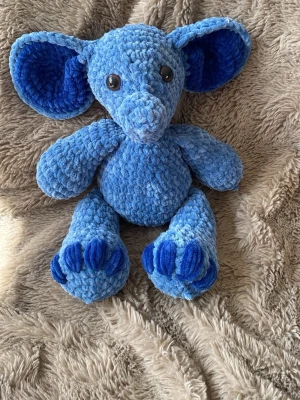 Blått gosedjur elefant - Mysig blå elefant i mjukt plyschmaterial med stora öron och broderade detaljer på tassarna. Elefanten har svarta plastögon och är perfekt som kramkompis eller dekoration i rummet.