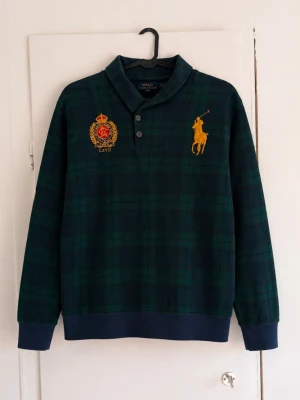 Ralph Lauren tröja  - Säljer en mörkgrön och marinblå rutig tröja från Polo Ralph Lauren med stora broderade detaljer framtill. Klassisk och stilren modell som passar perfekt till höst och vinter. Perfekt för vintage stil då den är svår att hitta! ✔️ Original från Polo Ralph Lauren ✔️ Broderad Big Pony-logga och emblem ✔️ Unikt rutigt mönster ✔️ Bekväm passform och hög kvalitet.                              Bra skick men lite sliten!