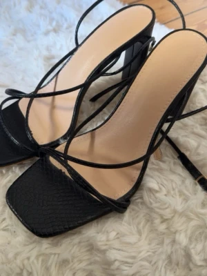 Svarta strappy pumps med fyrkantig tå - Snygga svarta pumps med tunna remmar och fyrkantig tå. Snörningen kan gå en bit upp på smalbenet