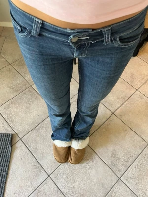 Mörkblå lågmidjade jeans - Säljer ett par mörkblå bootcut jeans med låg midja. Jeansen har snygga kontrastsömmar och är tillverkade i stretchigt denimtyg som sitter tajt över låren och släpper ut lite vid bensluten. Perfekta till vardagen! Storlek 32-34! 