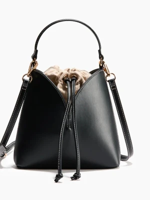 Svart bucket bag - Stilren svart bucket bag i slätt konstläder med kontrastsömmar och guldfärgade detaljer. Väskan har både handtag och justerbar axelrem samt en beige innerpåse med dragsko. Perfekt för dig som gillar minimalistisk design och praktiska detaljer.