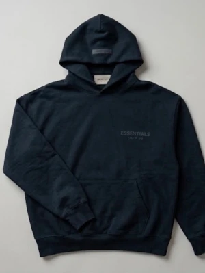 Svart Essentials Fear of God hoodie - Svart hoodie från Essentials Fear of God med diskret logga på bröstet och stor logga på ryggen. Klassisk känguruficka framtill, ribbade muddar och huva. Perfekt för en avslappnad streetwear-look. Kan köpa matchande byxor. Dm för fler bilder.