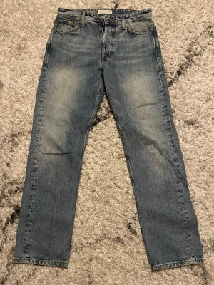 Ljusblå loose fit jeans Jack & Jones - Säljer ett par ljusblå loose fit jeans från Jack & Jones. Jeansen har klassisk femficksmodell, raka ben och snygg slitning på låren. Tillverkade i bomull för en bekväm känsla och avslappnad stil. Perfekta för dig som gillar en lite mer relaxed look.