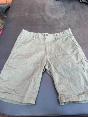 Gröna slim fit shorts från Bowery - Snygga gröna shorts från Bowery i slim fit-modell. De har klassisk midja, bälteshällor och stängs med knapp och dragkedja. Perfekta för varma dagar och enkla att matcha med olika stilar.
