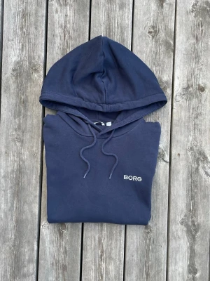 Björn Borg Hoodie | Svart - Strl M - Björn Borg hoodie i svart  ✔️ Storlek M ✔️ Snygg svart färg ✔️ Stilren Björn Borg-design ✔️ Fint skick (liten imperfektion vid fickan, skriv för bilder)  Packas noggrant och skickas snabbt! Vid önskan kan den skickas nytvättad, men tänk på att leveransen då kan dröja lite extra.  Hör gärna av dig om du undrar något, vill ha fler mått eller bara har en dålig dag ❤️ Jag är alltid öppen för bud!
