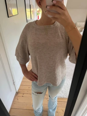 Beige stickad tröja med vida ärmar - Säljer en beige stickad tröja med rund hals och trekvarts, vida ärmar. Tröjan har en avslappnad passform och är gjord i ett mjukt, tunt stickat material. Perfekt för lager på lager och enkel att styla till jeans eller kjol.