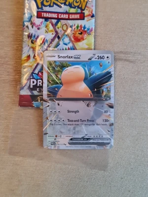 Pokémon Snorlax GX-kort och booster - Säljer ett Pokémon Snorlax GX samlarkort med 260 HP och två attacker, samt en oöppnad booster pack från Pokémon Trading Card Game. Perfekt för dig som gillar att samla eller spela Pokémonkort. Kortet har en glansig yta och färgstark design.