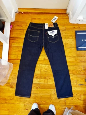 Levi's 505 raka jeans mörkblå - Säljer ett par klassiska Levi's 505 jeans i mörkblå denim med raka ben och snygga kontrastsömmar. Modellen har fem fickor, knappgylf och ikonisk läderpatch bak i midjan. Perfekta för dig som gillar tidlös och clean stil.