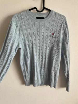 Bondelid ljusblå kabelstickad tröja - Strl S - Fin ljusblå kabelstickad tröja från Bondelid med klassiskt emblem på bröstet. 🩵 Snygg och stilren modell som passar bra till både jeans och andra outfits. Fint stickad struktur och i fint skick.