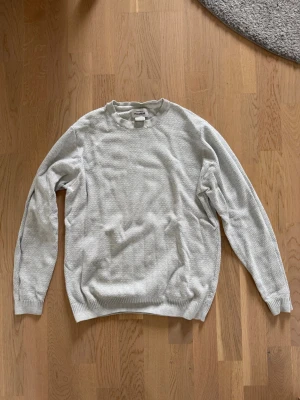 Ljusgrå stickad tröja Pull&Bear - Snygg ljusgrå stickad tröja från Pull&Bear i storlek M. Tröjan har rund halsringning, ribbade muddar och en diskret struktur i materialet. Perfekt för lager på lager och enkel att matcha med olika outfits.