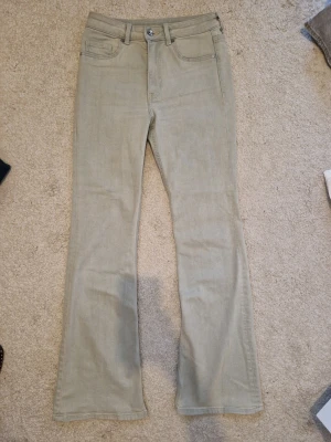 Grå bootcut jeans - Snygga grå jeans med bootcut passform och klassisk femficksdesign. Jeansen har bälteshällor, knappgylf och är tillverkade i ett mjukt denimtyg. Perfekta för dig som gillar en avslappnad men trendig stil.