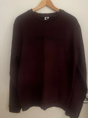 Vinröd sweatshirt med brodyr - Mysig vinröd sweatshirt med texten 'O NATIONALITY' broderat på bröstet. Tröjan har rund halsringning och ribbade muddar vid ärmslut och nederkant. Perfekt för en avslappnad och stilren look. Nypris ≈ 1500