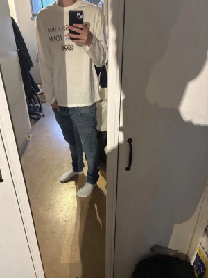 Vit långärmad Acne Studios t-shirt - Vit långärmad t-shirt från Acne Studios med tryck 'Acne Studios STOCKHOLM 1996' på bröstet. Klassisk passform och rund halsringning. Perfekt för en clean och stilren look.