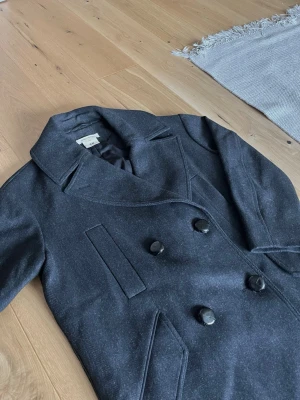 Isabel Marant x H&M trenchcoat - Isabel Marant x H&M trenchcoat/rock i princip i nyskick. Jackan har riktigt hög kvalitet. Storleken är EUR 38 (passar M/L). Jackan är gjord 75% av ull. Mätningarna är: 54cm axel till axel. 59cm pit till pit. 97cm i längd (topp till botten). (Jackan passar mig bra som är 183cm.) Skriv vid funderingar. Skickar inom 24 timmar! ”OBS. JACKAN ÄR SVART. EJ MARINBLÅ”