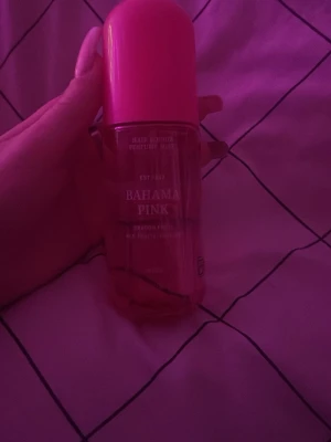 Bahama Pink parfym mist - En parfym mist, Flaskan är genomskinlig med rosa vätska och har ett stort rosa lock. Designen är enkel och modern, perfekt för dig som gillar fräscha och söta dofter. Flaskan är smidig att ta med i väskan.