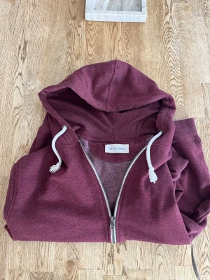 Vinröd hoodie - Snygg vinröd hoodie från Pier One med dragkedja framtill och vita dragsnören i huvan. Perfekt för en avslappnad stil. Tillverkad i mjukt material som känns skönt mot huden.