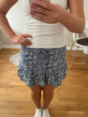 Blå kjol med inbyggda shorts - Superfin mörkblå blommig kjol med inbyggda shorts från Zara i storlek M. Har nån liten fläck (se bild 6). Pris kan alltid diskuteras och skriv om du har några frågor!🩷