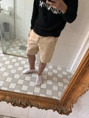 Beige shorts från Selected Homme - Snygga beige shorts från Selected Homme i ett mjukt bomullsmaterial. Klassisk passform med midja och raka ben, perfekta för varma dagar. Stilsäker och enkel design som funkar till det mesta.