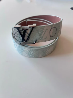 Vit blått bälte med silver spänne - Ni ser märket, vitt/ljusblått fint mönster, silvrigt spänne, aldrig använd,110cm